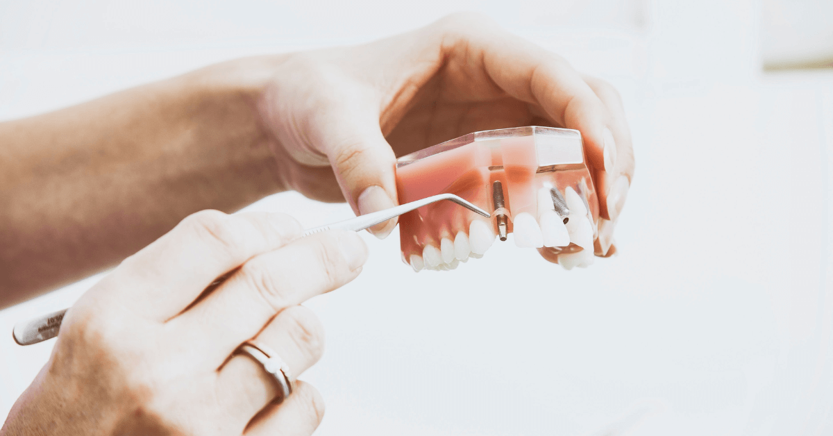 Close up of hands holding dentures and a cleaning tool