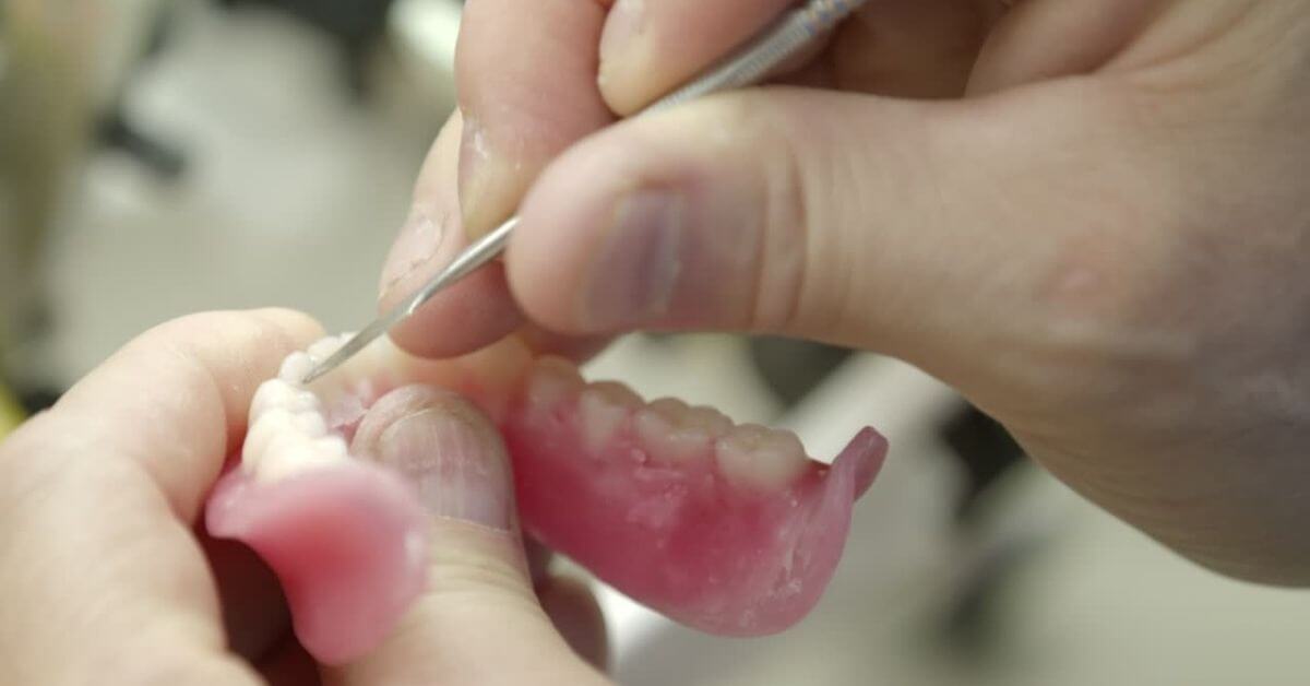 Close up of hands holding and cleaning dentures