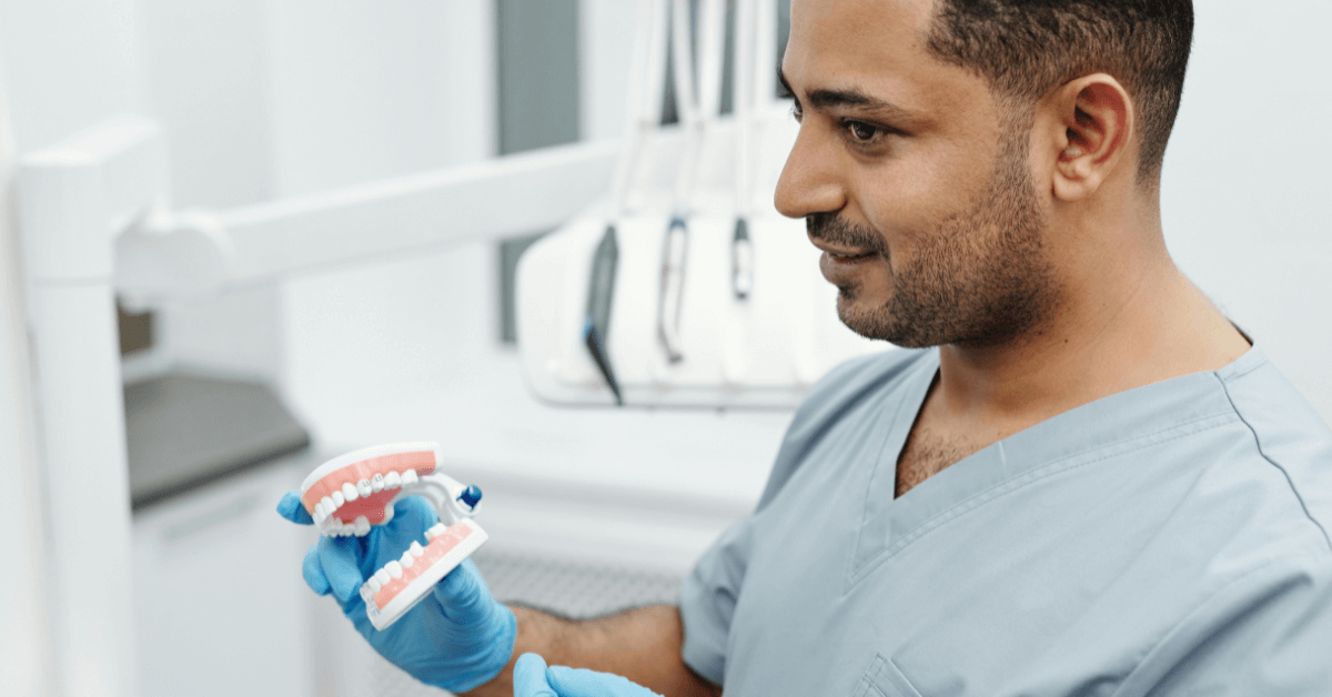 denture technician looking at sculpture of teeth